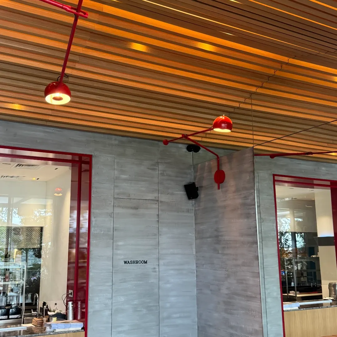 Red lamps on long arms under the timber ceiling, beside the washroom and kitchen windows