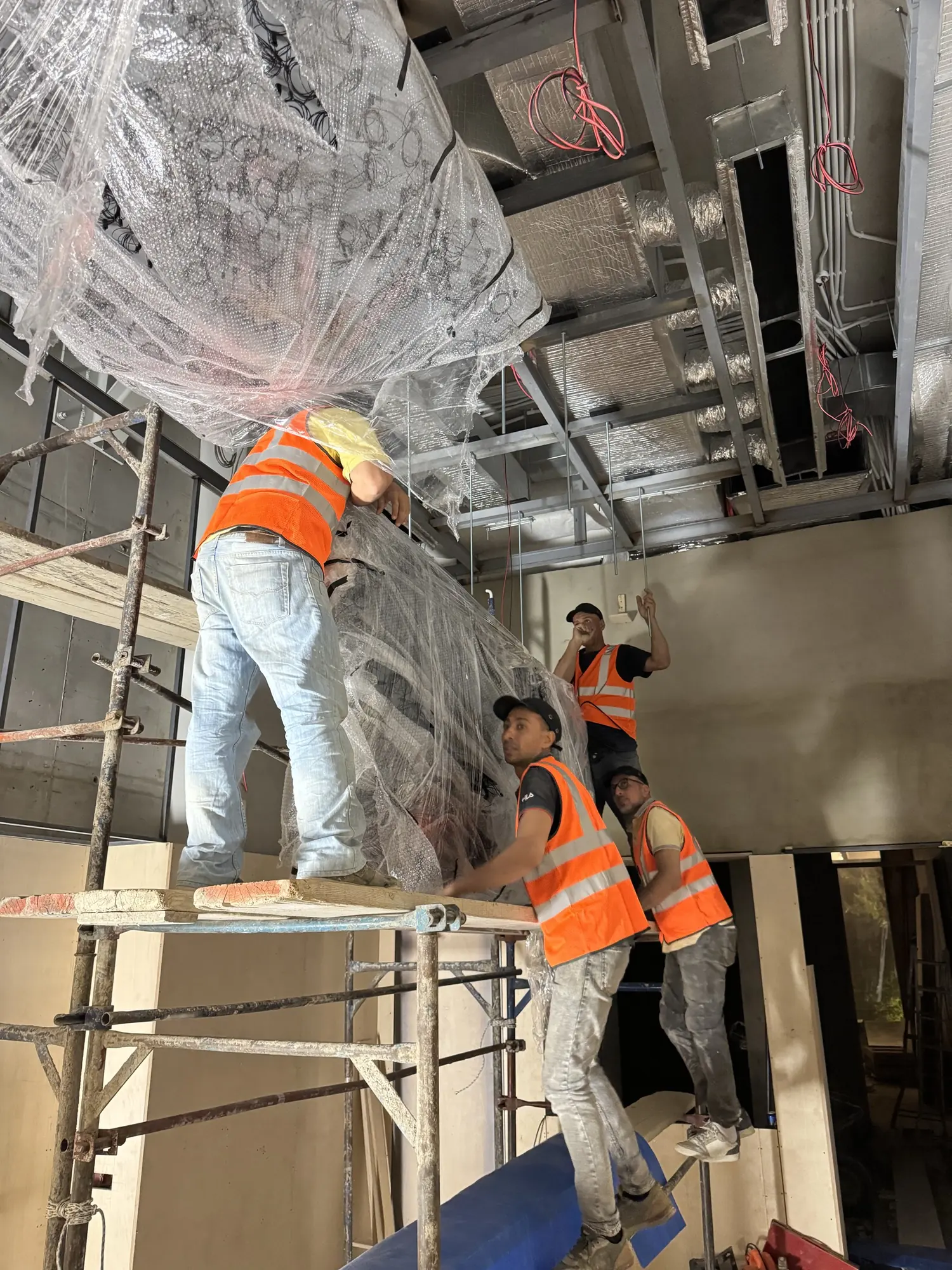 Four installers on scaffolding fixing the ceiling plate