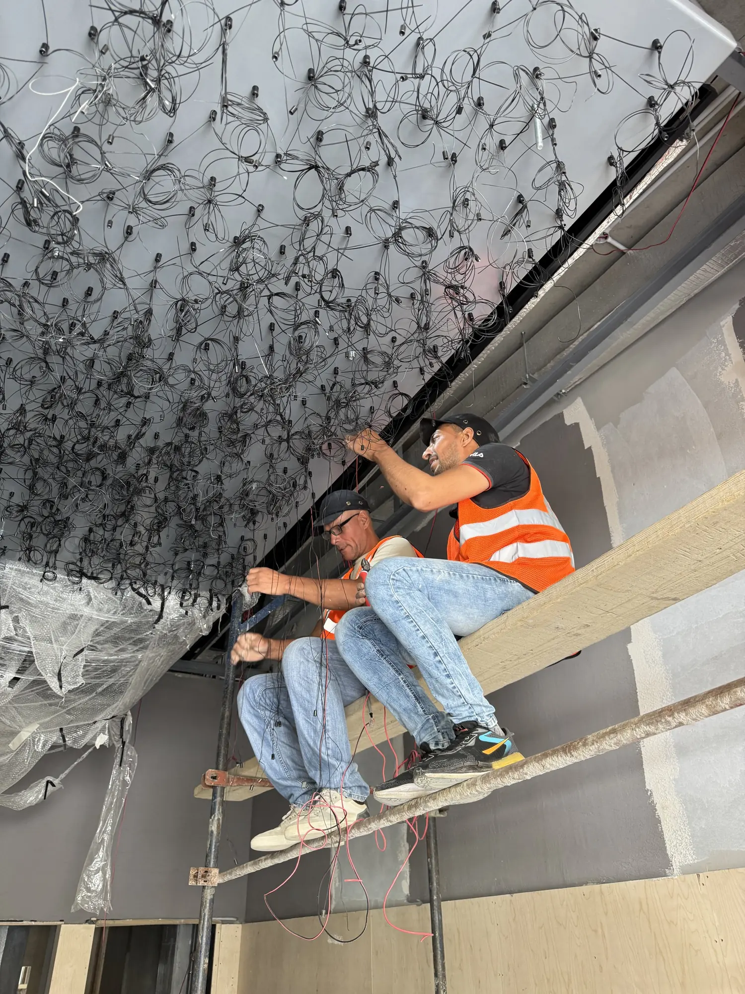Two installers on scaffolding beneath the ceiling cabling