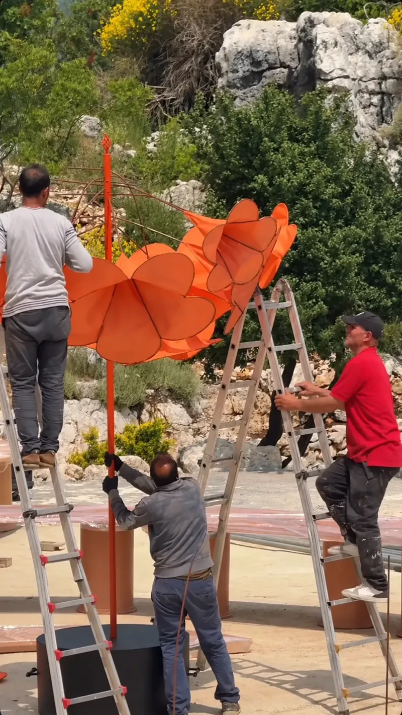 Three installers on ladders raising the blossom tree onto its pole